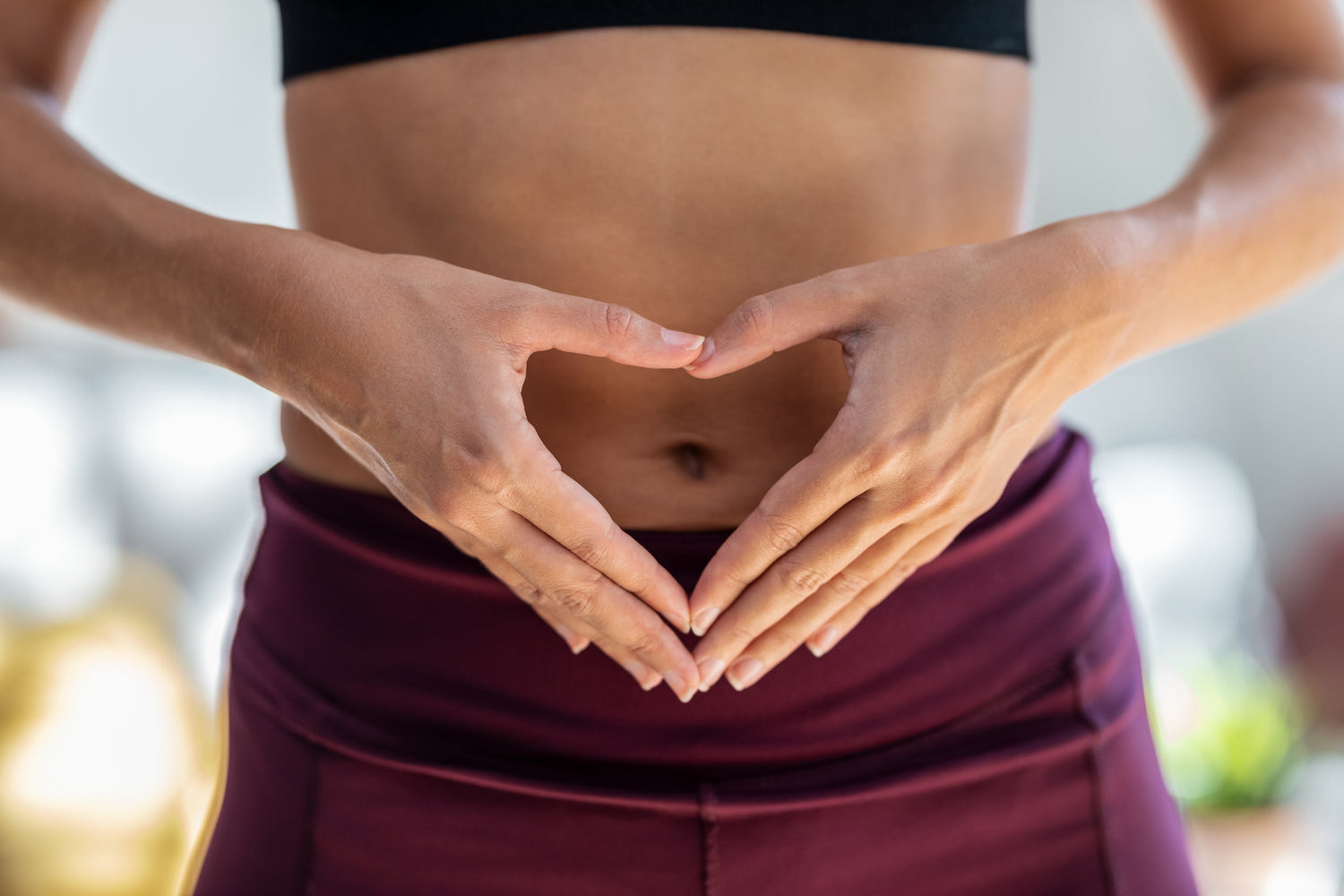 Person making a heart shape with their hands over their stomach